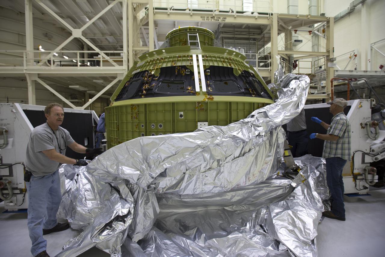 Inside the Neil Armstrong Operations and Checkout Building high bay at NASA's Kennedy Space Center in Florida, Lockheed Martin technicians remove the protective covering from the Orion crew module structural test article (STA). The STA arrived aboard NASA's Super Guppy aircraft at the Shuttle Landing Facility operated by Space Florida. The test article was moved inside the facility's high bay for further testing. The Orion spacecraft will launch atop NASA’s Space Launch System rocket on EM-1, its first deep space mission, in late 2018.
