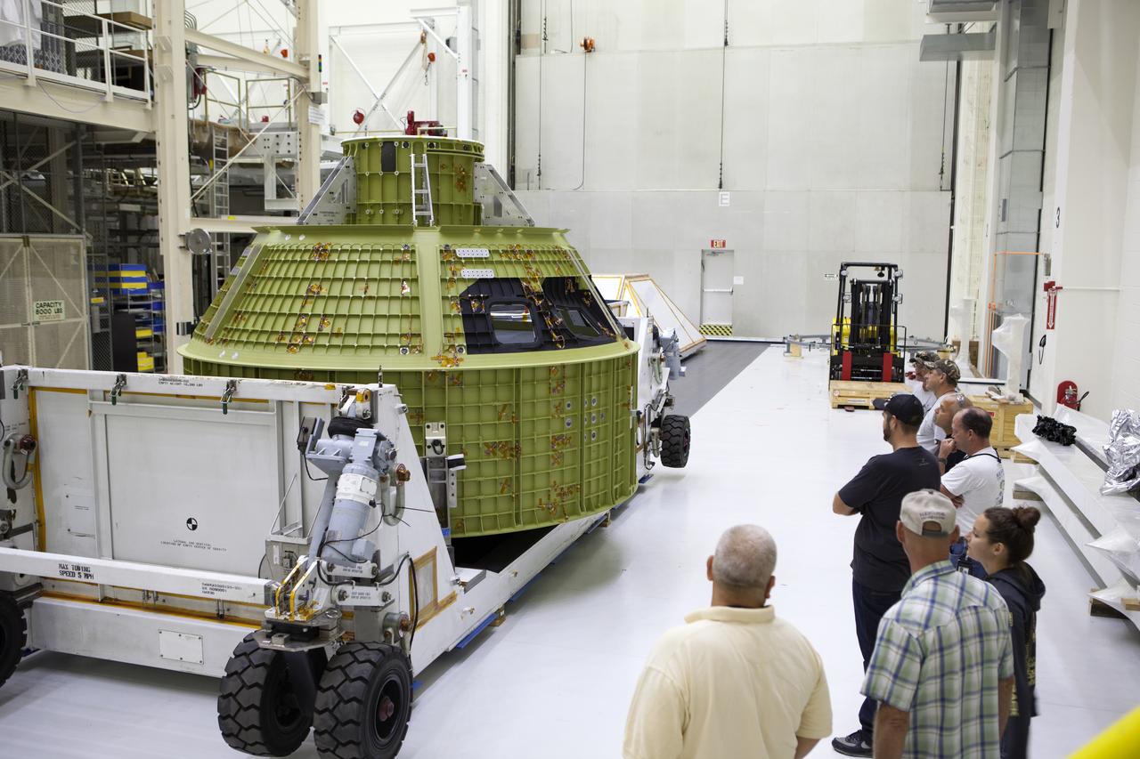 Inside the Neil Armstrong Operations and Checkout Building high bay at NASA's Kennedy Space Center in Florida, technicians with Lockheed Martin look over the Orion crew module structural test article (STA) secured on the bottom of its transport container. The STA arrived aboard NASA's Super Guppy aircraft at the Shuttle Landing Facility operated by Space Florida. The test article was moved inside the facility's high bay for further testing. The Orion spacecraft will launch atop NASA’s Space Launch System rocket on EM-1, its first deep space mission, in late 2018.
