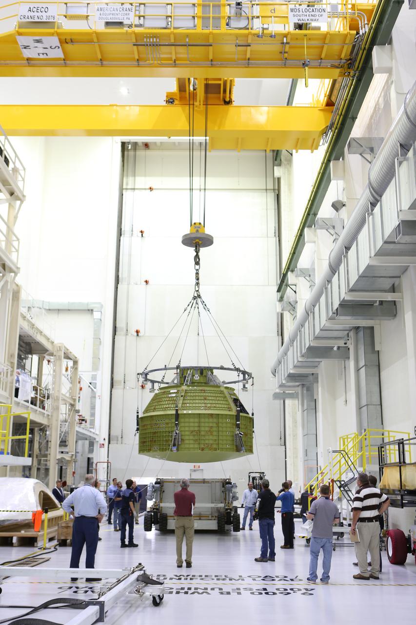 Inside the Neil Armstrong Operations and Checkout Building at NASA’s Kennedy Space Center in Florida, Lockheed Martin technicians monitor the progress as a crane lifts the Orion crew module structural test article (STA) away from the base of its transport container. The STA arrived aboard NASA's Super Guppy aircraft at the Shuttle Landing Facility operated by Space Florida. The test article will be moved to a test tool called the birdcage for further testing. The Orion spacecraft will launch atop NASA’s Space Launch System rocket on EM-1, its first deep space mission, in late 2018.