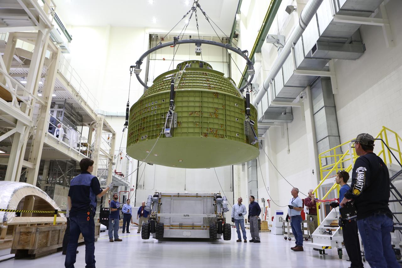 Inside the Neil Armstrong Operations and Checkout Building at NASA’s Kennedy Space Center in Florida, Lockheed Martin technicians monitor the progress as a crane moves the Orion crew module structural test article (STA) along the center aisle of the high bay. The STA arrived aboard NASA's Super Guppy aircraft at the Shuttle Landing Facility operated by Space Florida. The test article will be moved to a test tool called the birdcage for further testing. The Orion spacecraft will launch atop NASA’s Space Launch System rocket on EM-1, its first deep space mission, in late 2018.