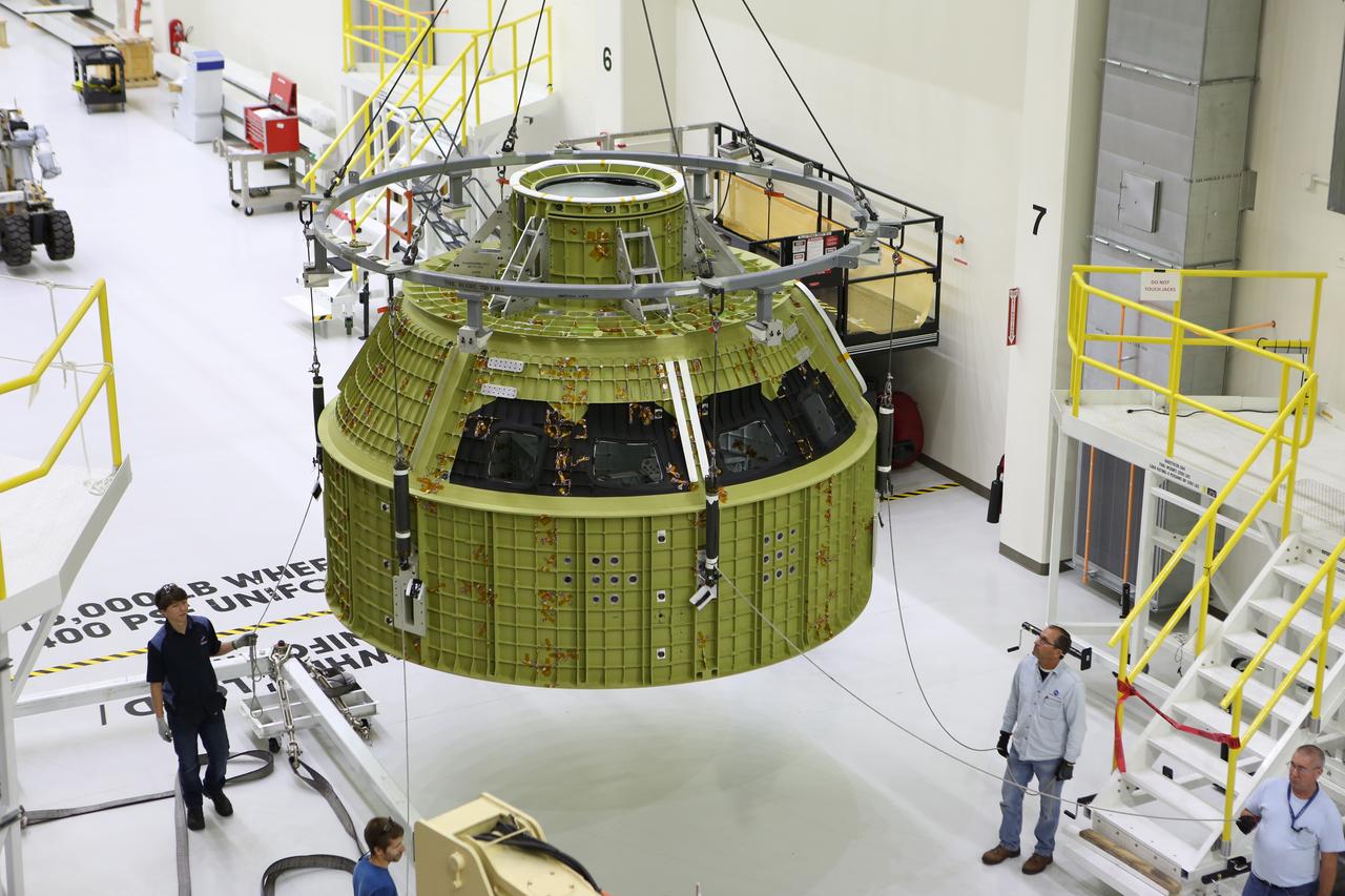 Inside the Neil Armstrong Operations and Checkout Building at NASA’s Kennedy Space Center in Florida, Lockheed Martin technicians monitor the progress as a crane moves the Orion crew module structural test article (STA) along the center aisle of the high bay. The STA arrived aboard NASA's Super Guppy aircraft at the Shuttle Landing Facility operated by Space Florida. The test article will be moved to a test tool called the birdcage for further testing. The Orion spacecraft will launch atop NASA’s Space Launch System rocket on EM-1, its first deep space mission, in late 2018.