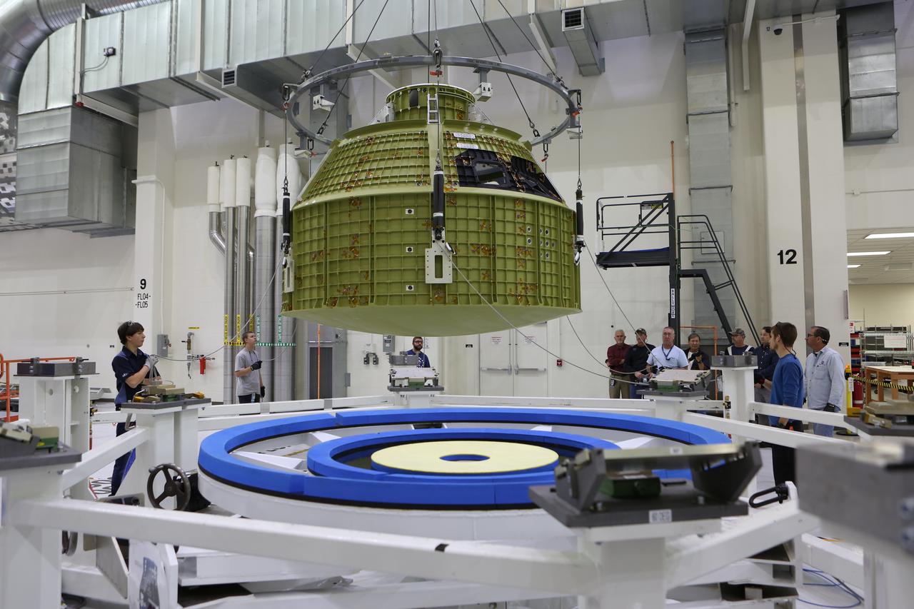 Inside the Neil Armstrong Operations and Checkout Building at NASA’s Kennedy Space Center in Florida, Lockheed Martin technicians monitor the progress as a crane lowers the Orion crew module structural test article (STA) toward a test tool called the birdcage. The STA arrived aboard NASA's Super Guppy aircraft at the Shuttle Landing Facility operated by Space Florida. The test article will be secured on the birdcage for further testing. The Orion spacecraft will launch atop NASA’s Space Launch System rocket on EM-1, its first deep space mission, in late 2018.