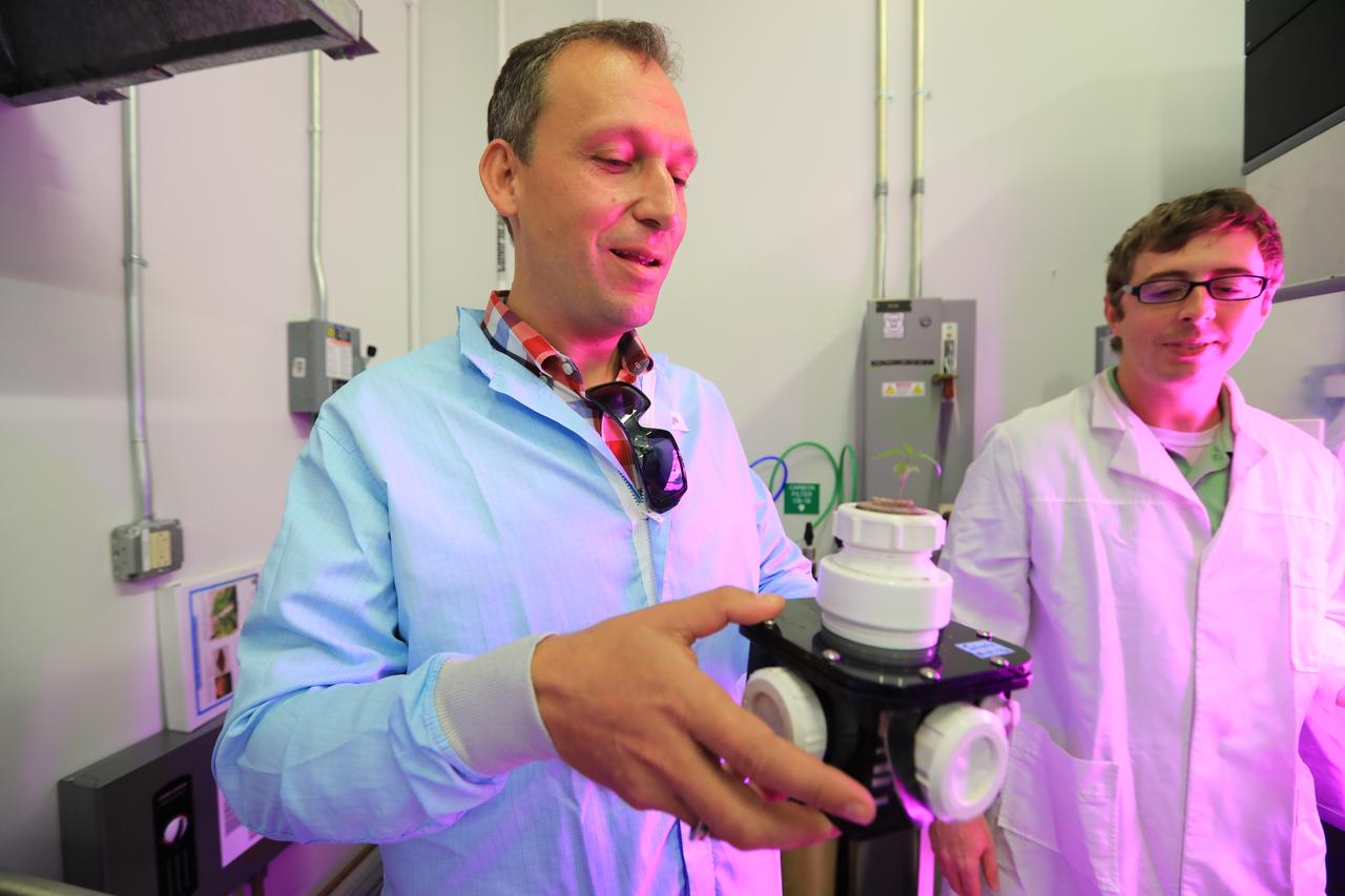 While touring the Space Station Processing Facility at NASA's Kennedy Space Center in Florida, Thomas Zurbuchen, in plaid shirt, NASA's associate administrator for the Science Mission Directorate, examines a device to grow plants in space. 