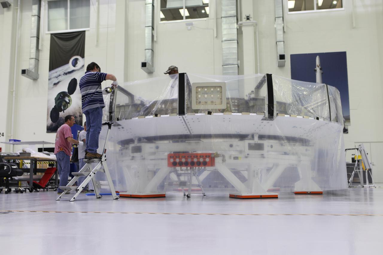 Inside the Neil Armstrong Operations and Checkout Building high bay at NASA's Kennedy Space Center in Florida, Lockheed Martin technicians secure a protective cover around the Orion crew module adapter (CMA) for Exploration Mission 1 (EM-1) for its move to a clean. The CMA will undergo propellant and environmental control and life support system tube installation and welding. The adapter will connect the Orion crew module to the European Space Agency-provided service module. The Orion spacecraft will launch atop NASA’s Space Launch System rocket on EM-1, its first deep space mission, in late 2018. 