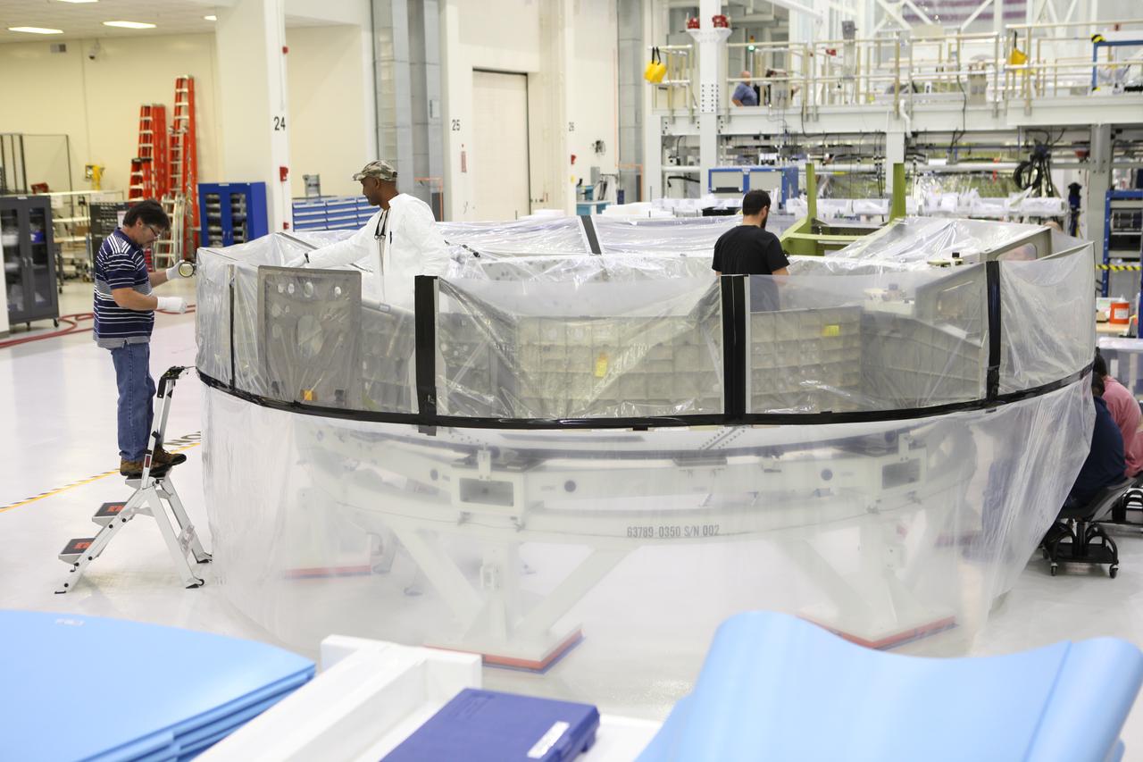 Inside the Neil Armstrong Operations and Checkout Building high bay at NASA's Kennedy Space Center in Florida, Lockheed Martin technicians secure a protective cover around the Orion crew module adapter (CMA) for Exploration Mission 1 (EM-1) for its move to a clean room. The CMA will undergo propellant and environmental control and life support system tube installation and welding. The adapter will connect the Orion crew module to the European Space Agency-provided service module. The Orion spacecraft will launch atop NASA’s Space Launch System rocket on EM-1, its first deep space mission, in late 2018.