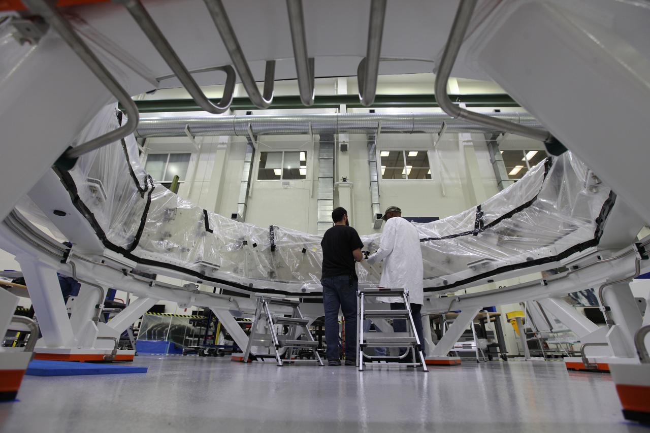 Inside the Neil Armstrong Operations and Checkout Building high bay at NASA's Kennedy Space Center in Florida, Lockheed Martin technicians secure a protective cover around the Orion crew module adapter (CMA) for Exploration Mission 1 (EM-1) for its move to a clean room. The CMA will undergo propellant and environmental control and life support system tube installation and welding. The adapter will connect the Orion crew module to the European Space Agency-provided service module. The Orion spacecraft will launch atop NASA’s Space Launch System rocket on EM-1, its first deep space mission, in late 2018. 