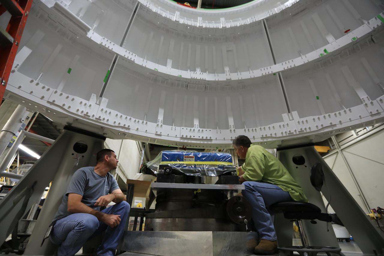 Inside the Booster Fabrication Facility at NASA's Kennedy Space Center in Florida, the left hand aft skirt for the agency's Space Launch System (SLS) rocket is ready for the assembly process. From left, are Chad Goetz, quality technician with Orbital ATK, and Robbie Blaue, quality assurance specialist with the Defense Contract Management Agency. The aft skirt was refurbished and painted in support facilities at the Hangar AF facility at Cape Canaveral Air Force Station in Florida. The space shuttle-era aft skirt will be used on the left hand booster of the SLS for Exploration Mission 1 (EM-1). NASA is preparing for EM-1, deep space missions, and the Journey to Mars. 