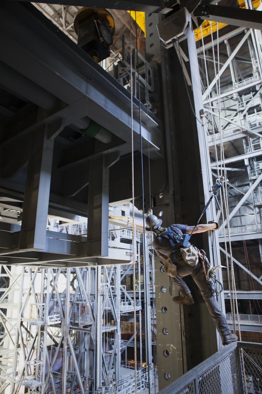 Inside the Vehicle Assembly Building (VAB) at NASA’s Kennedy Space Center in Florida, a construction worker watches as the first half of the B-level work platforms, B south, for NASA’s Space Launch System (SLS) rocket is lowered into place in High Bay 3. Construction workers will secure the large bolts that hold the platform in place on the south wall. The B platforms are the ninth of 10 levels of work platforms that will surround and provide access to the SLS rocket and Orion spacecraft for Exploration Mission 1. The Ground Systems Development and Operations Program is overseeing upgrades and modifications to VAB High Bay 3, including installation of the new work platforms, to prepare for NASA’s Journey to Mars.