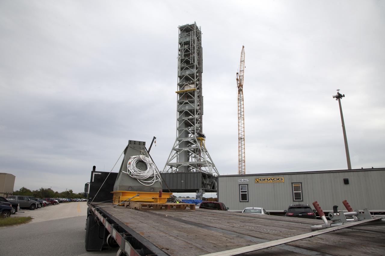 A flatbed truck carries a vertical support post (VSP) for NASA's Space Launch System (SLS) rocket to the Mobile Launcher Yard at NASA's Kennedy Space Center in Florida. The two aft skirt electrical umbilicals (ASEUs) and the first of the vehicle support posts underwent a series of tests to confirm they are functioning properly and ready to support the SLS for launch. The ASEUs will connect to the SLS rocket at the bottom outer edge of each booster and provide electrical power and data connections to the rocket until it lifts off from the launch pad. The eight VSPs will support the load of the solid rocket boosters, with four posts for each of the boosters. The center’s Engineering Directorate and the Ground Systems Development and Operations Program are overseeing processing and testing of the umbilicals. 