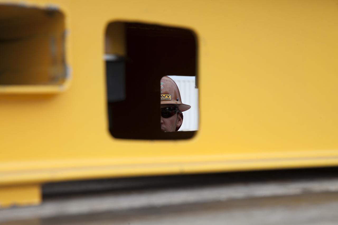 A construction worker is in view as a flatbed truck passes by carrying a vertical support post (VSP) for NASA's Space Launch System (SLS) rocket to the Mobile Launcher Yard at NASA's Kennedy Space Center in Florida. The two aft skirt electrical umbilicals (ASEUs) and the first of the vehicle support posts underwent a series of tests to confirm they are functioning properly and ready to support the SLS for launch. The ASEUs will connect to the SLS rocket at the bottom outer edge of each booster and provide electrical power and data connections to the rocket until it lifts off from the launch pad. The eight VSPs will support the load of the solid rocket boosters, with four posts for each of the boosters. The center’s Engineering Directorate and the Ground Systems Development and Operations Program are overseeing processing and testing of the umbilicals.