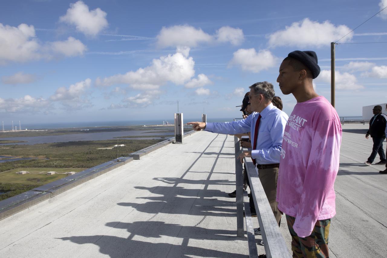 During a tour for cast and crew members of the upcoming motion picture "Hidden Figures," Kennedy Space Center Director Bob Cabana points to Launch Pads 39A and 39B from the roof of the Vehicle Assembly Building. In the foreground is Pharrell Williams, musician and producer of “Hidden Figures." The movie is based on the book of the same title, by Margot Lee Shetterly. It chronicles the lives of Katherine Johnson, Dorothy Vaughan and Mary Jackson, three African-American women who worked for NASA as human "computers.” Their mathematical calculations were crucial to the success of Project Mercury missions including John Glenn’s orbital flight aboard Friendship 7 in 1962. The film is due in theaters in January 2017.