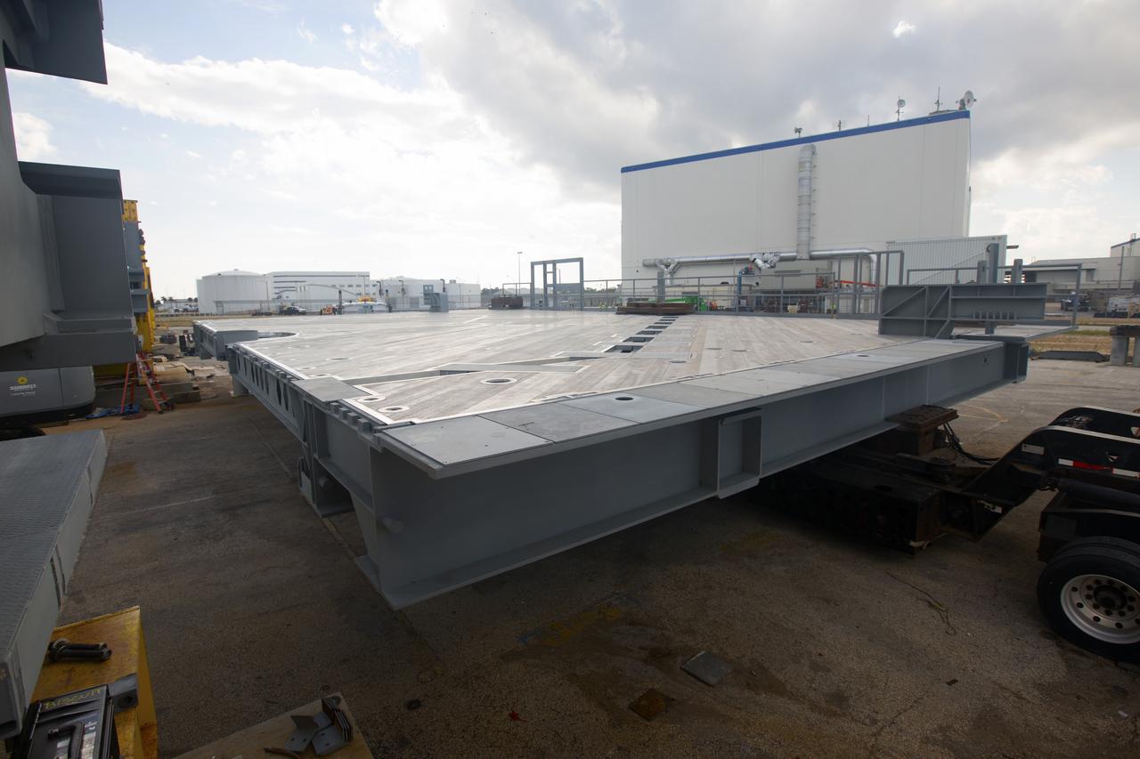 A heavy load transport truck from Tillett Heavy Hauling in Titusville, Florida, arrives in a staging area near the Vehicle Assembly Building (VAB) at NASA’s Kennedy Space Center in Florida, carrying the second half of the A-level work platforms, A north, for the agency’s Space Launch System (SLS) rocket. This is the final platform delivered to Kennedy. The A-level platforms are the topmost platforms for High Bay 3 in the Vehicle Assembly Building (VAB). The platform will be delivered to the VAB staging area in the west parking lot. The Ground Systems Development and Operations Program is overseeing upgrades and modifications to High Bay 3 to support processing of the SLS and Orion spacecraft. A total of 10 levels of new platforms, 20 platform halves altogether, will surround the SLS rocket and Orion spacecraft and provide access for testing and processing.