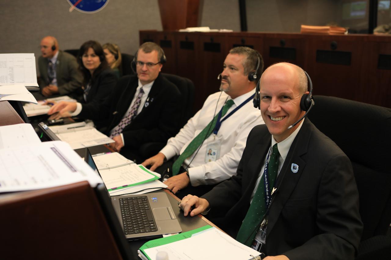 In the Mission Director's Center at Cape Canaveral Air Force Station, Omar Baez, a senior launch director in NASA's Launch Services Program at the agency's Kennedy Space Center in Florida, center, monitors the progress of preparations to launch eight Cyclone Global Navigation Satellite System, or CYGNSS, spacecraft. Seated to his left, facing the camera, is Tim Dunn, launch director for the CYGNSS mission. The CYGNSS satellites will make frequent and accurate measurements of ocean surface winds throughout the life cycle of tropical storms and hurricanes. The data that CYGNSS provides will enable scientists to probe key air-sea interaction processes that take place near the core of storms, which are rapidly changing and play a crucial role in the beginning and intensification of hurricanes. 