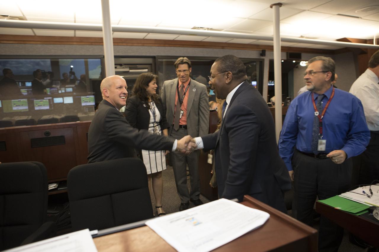In the Mission Director's Center at Cape Canaveral Air Force Station,  Greg Robinson, deputy associate administrator for Programs in the NASA Science Mission Directorate, right, congratulates, Tim Dunn, who was launch director for launch of eight Cyclone Global Navigation Satellite System, or CYGNSS, spacecraft. The satellites will make frequent and accurate measurements of ocean surface winds throughout the life cycle of tropical storms and hurricanes. The data that CYGNSS provides will enable scientists to probe key air-sea interaction processes that take place near the core of storms, which are rapidly changing and play a crucial role in the beginning and intensification of hurricanes.