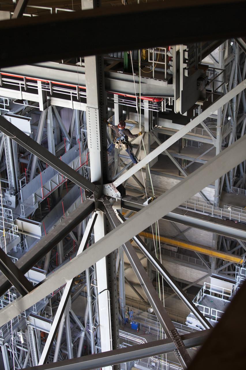 A construction worker wearing a safety harness and tethered lines prepares to assist with the installation of the second half of the B-level work platforms, B north, for NASA’s Space Launch System (SLS) rocket, high up in the Vehicle Assembly Building (VAB) at NASA’s Kennedy Space Center in Florida. The B platform will be installed on the north side of High Bay 3. The B platforms are the ninth of 10 levels of work platforms that will surround and provide access to the SLS rocket and Orion spacecraft for Exploration Mission 1. The Ground Systems Development and Operations Program is overseeing upgrades and modifications to VAB High Bay 3, including installation of the new work platforms, to prepare for NASA’s Journey to Mars. 