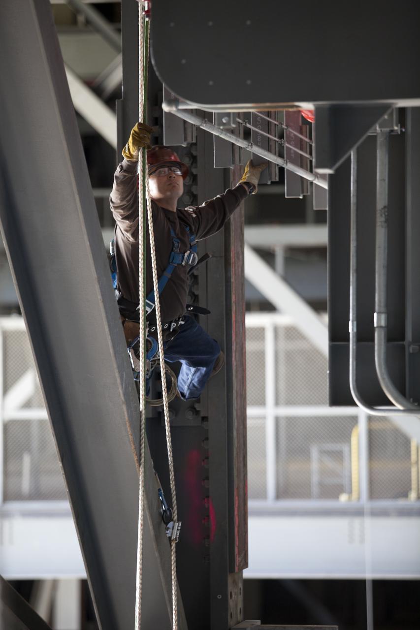 A construction worker wearing a safety harness and tethered lines prepares to assist with the installation of the second half of the B-level work platforms, B north, for NASA’s Space Launch System (SLS) rocket, high up in the Vehicle Assembly Building (VAB) at NASA’s Kennedy Space Center in Florida. The B platform will be installed on the north side of High Bay 3. The B platforms are the ninth of 10 levels of work platforms that will surround and provide access to the SLS rocket and Orion spacecraft for Exploration Mission 1. The Ground Systems Development and Operations Program is overseeing upgrades and modifications to VAB High Bay 3, including installation of the new work platforms, to prepare for NASA’s Journey to Mars.