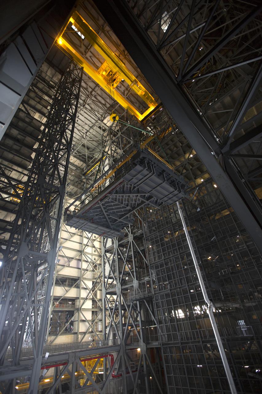 A crane lifts the second half of the B-level work platforms, B north, for NASA's Space Launch System (SLS) rocket, high up in the transfer aisle of the Vehicle Assembly Building (VAB) at NASA’s Kennedy Space Center in Florida. The B north platform will lowered into High Bay 3 for installation on the north side of the high bay. The B platforms are the ninth of 10 levels of work platforms that will surround and provide access to the SLS rocket and Orion spacecraft for Exploration Mission 1. The Ground Systems Development and Operations Program is overseeing upgrades and modifications to VAB High Bay 3, including installation of the new work platforms, to prepare for NASA’s Journey to Mars. 