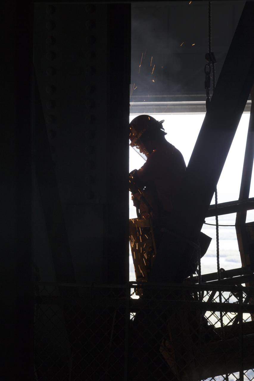 A construction worker makes adjustments to a section of steel during the installation of the second half of the B-level work platforms, B north, for NASA's Space Launch System (SLS) rocket, in High Bay 3 in the Vehicle Assembly Building (VAB) at NASA's Kennedy Space Center in Florida. Construction workers will secure the large bolts that hold the platform in place on the north wall. The B platforms are the ninth of 10 levels of work platforms that will surround and provide access to the SLS rocket and Orion spacecraft for Exploration Mission 1. The Ground Systems Development and Operations Program is overseeing upgrades and modifications to VAB High Bay 3, including installation of the new work platforms, to prepare for NASA’s Journey to Mars. 