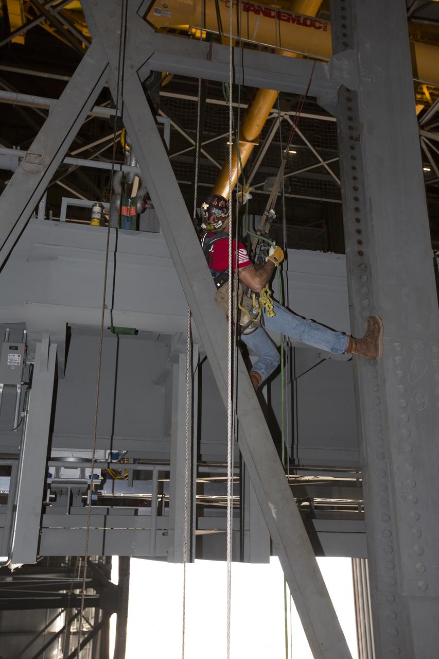A construction worker wearing a safety harness and tethered lines assists with the installation of the second half of the B-level work platforms, B north, for NASA’s Space Launch System (SLS) rocket, high up in the Vehicle Assembly Building (VAB) at NASA’s Kennedy Space Center in Florida. The B platform will be installed on the north side of High Bay 3. The B platforms are the ninth of 10 levels of work platforms that will surround and provide access to the SLS rocket and Orion spacecraft for Exploration Mission 1. The Ground Systems Development and Operations Program is overseeing upgrades and modifications to VAB High Bay 3, including installation of the new work platforms, to prepare for NASA’s Journey to Mars.