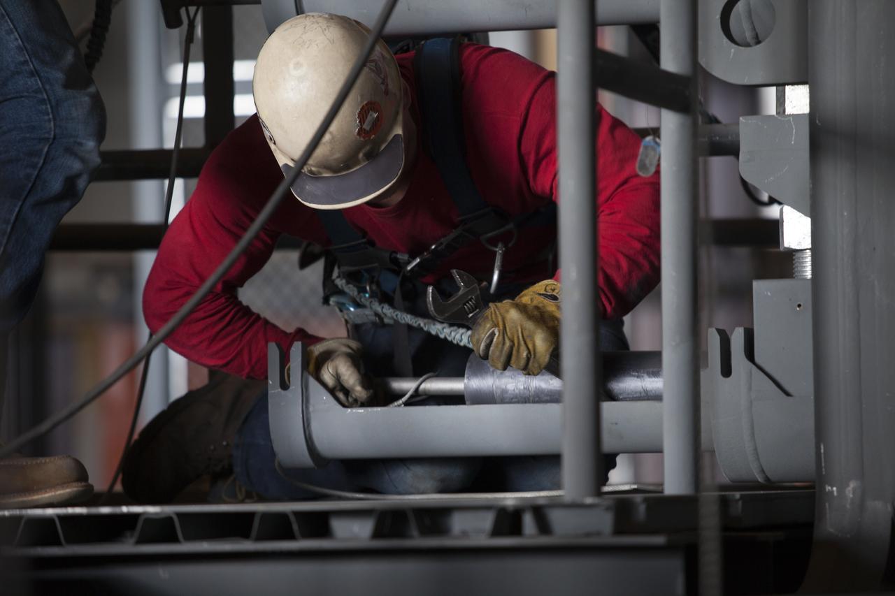 A construction worker wearing a safety harness and tethered lines turns a bolt to help secure the second half of the B-level work platforms, B north, for NASA's Space Launch System (SLS) rocket, during installation in High Bay 3 of the Vehicle Assembly Building (VAB) at NASA's Kennedy Space Center in Florida. The B platform is being installed on the north side of the high bay. The B platforms are the ninth of 10 levels of work platforms that will surround and provide access to the SLS rocket and Orion spacecraft for Exploration Mission 1. The Ground Systems Development and Operations Program is overseeing upgrades and modifications to VAB High Bay 3, including installation of the new work platforms, to prepare for NASA’s Journey to Mars. 