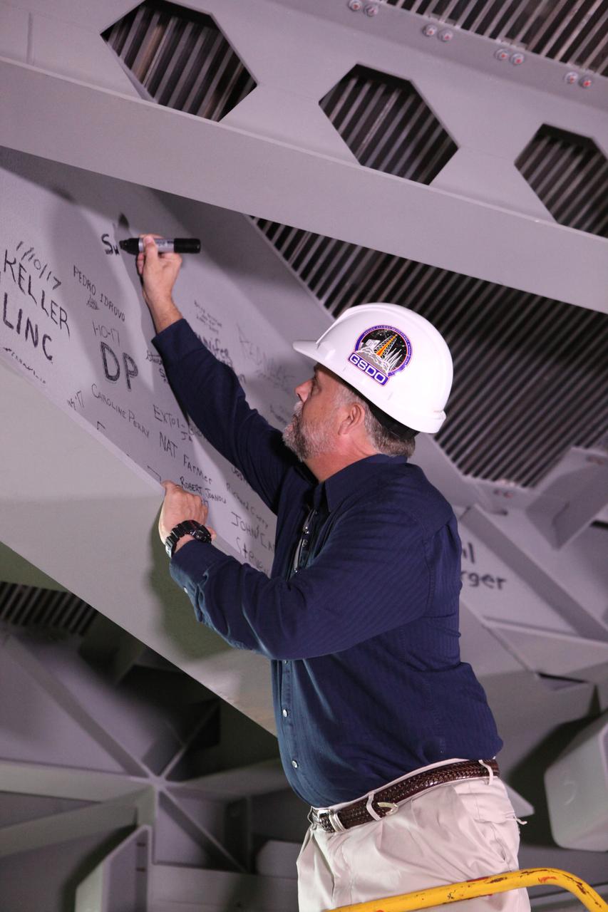 Shawn Quinn, associate program manager for the Ground Systems Development and Operations Program (GSDO), signs the platform A North beam in the transfer aisle of the Vehicle Assembly Building (VAB) at NASA's Kennedy Space Center in Florida. Kennedy's Engineering Directorate coordinated a platform beam signing event to celebrate the culmination of the NASA and contractor team's last several years of study, design, construction and installation of 20 new work platforms in High Bay 3 of the Vehicle Assembly (VAB). The platform will be installed and secured on its rail beam high up on the north wall of High Bay 3. The installation of the final topmost level completes the 10 levels of work platforms, 20 platform halves altogether, that will surround NASA's Space Launch System rocket and the Orion spacecraft and allow access during processing for missions, including the first uncrewed flight test of Orion atop the SLS rocket in 2018. GSDO, with support from the center's Engineering Directorate, is overseeing upgrades and modifications to the VAB, including installation of the new work platforms. 