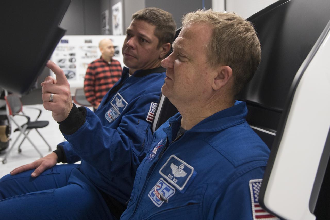 Astronauts Bob Behnken, left, and Eric Boe work in a mock-up of the SpaceX Crew Dragon flight deck at the company's Hawthorne, California, headquarters as development of the crew systems continues for eventual missions to the International Space Station.