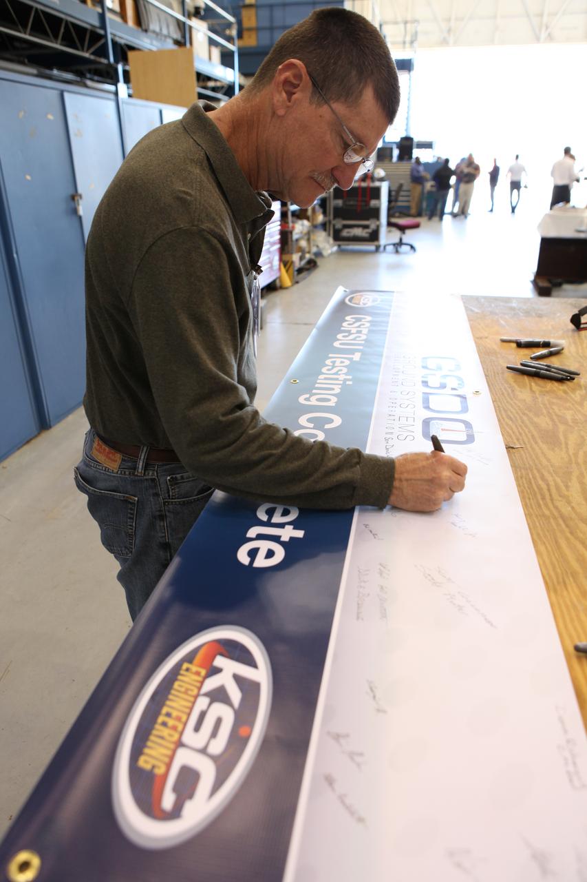A NASA technician signs the banner inside a support building at the Launch Equipment Test Facility at Kennedy Space Center in Florida. Testing of the Core Stage Forward Skirt Umbilical (CSFSU) for NASA's Space Launch System is complete and the umbilical has been transported to the mobile launcher area. The umbilical will be prepared for installation on the tower of the mobile launcher. The CSFSU will be mated to the core stage forward skirt to provide commodities to the SLS rocket, and then disconnect and swing away before launch. Its main purpose is to provide conditioned air and gaseous nitrogen to the SLS Core Stage Forward Skirt. The center’s Engineering Directorate and the Ground Systems Development and Operations Program are overseeing processing and testing of the umbilicals.