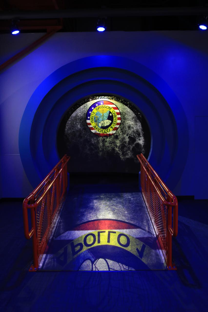 A gateway featuring the Apollo 1 mission logo over the moon is shown inside the new tribute to the crew of Apollo 1 who perished in a fire at the launch pad on Jan. 27, 1967, during training for the mission. Astronauts Gus Grissom, Ed White II and Roger Chaffee were lost during the fire. The tribute at the Apollo/Saturn V Center at NASA's Kennedy Space Center opened Jan. 27, 2017, 50 years after the crew of three was lost. It features numerous items recalling the lives of the three astronauts. The tribute also includes the three-part hatch to the spacecraft itself, the first time any part of the Apollo 1 spacecraft has been displayed publicly. A version of the hatch after it was redesigned is also showcased as an example of improvements NASA made throughout the agency and to the Apollo spacecraft that would later carry astronauts to the moon. 