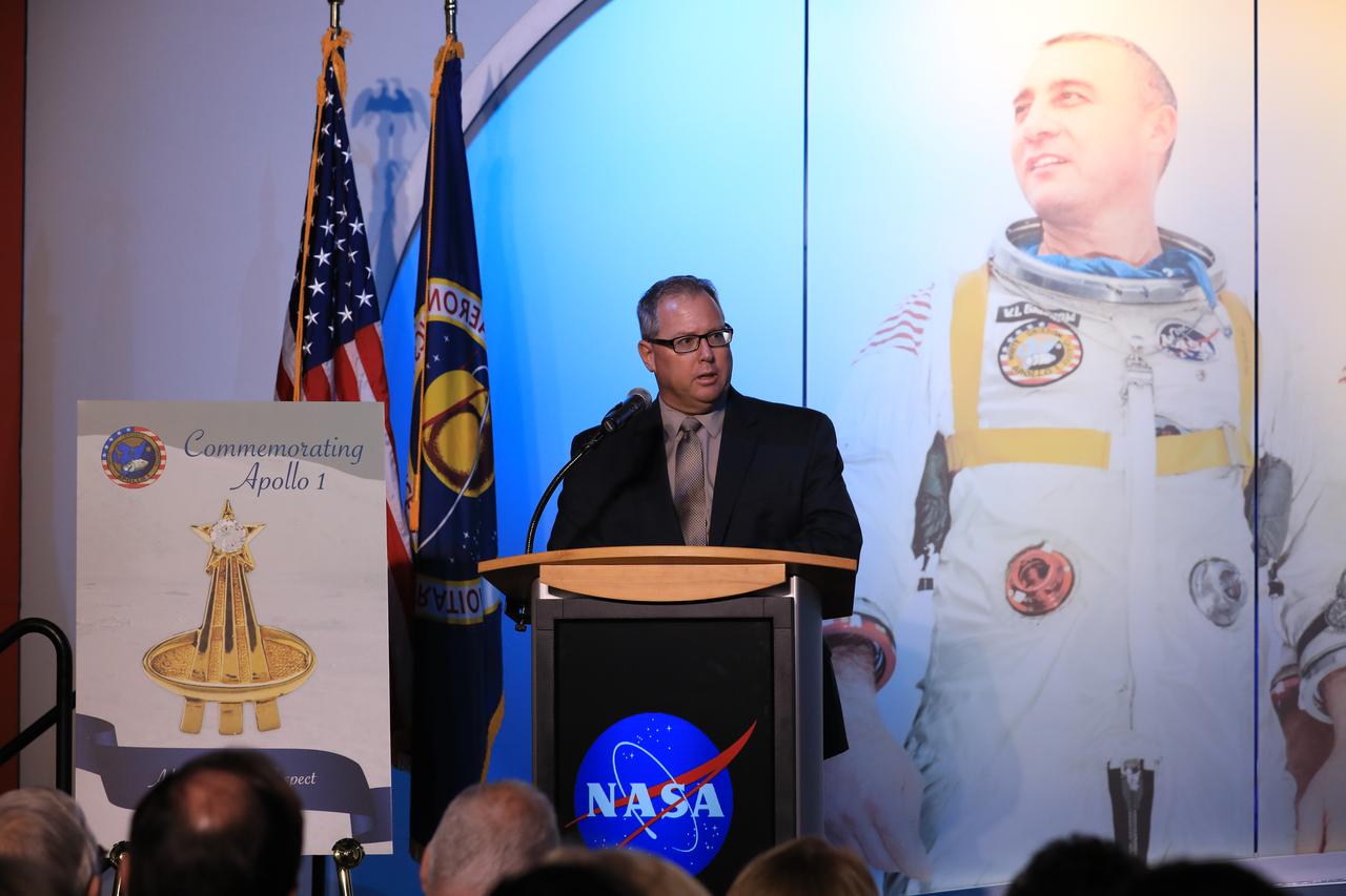Therrin Protze, Chief Operating Officer, Delaware North Corporation Parks & Resorts at KSC, Inc., speaks during the opening of the tribute exhibition to the Apollo 1 astronauts who perished in a fire at the launch pad on Jan. 27, 1967, during training for the mission. The tribute highlights the lives and careers of astronauts Gus Grissom, Ed White II and Roger Chaffee who were lost during the fire. The tribute at the Apollo/Saturn V Center at NASA's Kennedy Space Center opened Jan. 27, 2017, 50 years after the crew of three was lost. It features numerous items recalling the lives of the three astronauts. The tribute also includes the three-part hatch to the spacecraft itself, the first time any part of the Apollo 1 spacecraft has been displayed publicly. A version of the hatch after it was redesigned is also showcased as an example of improvements NASA made throughout the agency and to the Apollo spacecraft that would later carry astronauts to the moon.