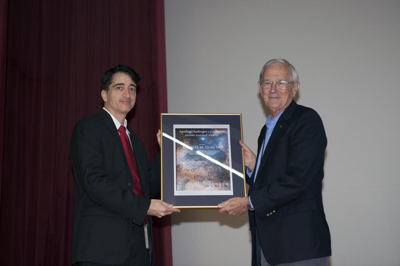 Mike Ciannilli, at left, the Apollo, Challenger, Columbia Lessons Learned Program manager, presents a certificate to Charlie Duke, former Apollo 16 astronaut and member of the Apollo 1 Emergency Egress Investigation Team, during the Apollo 1 Lessons Learned presentation in the Training Auditorium at NASA's Kennedy Space Center in Florida. The program's theme was "To There and Back Again." The event helped pay tribute to the Apollo 1 crew, Gus Grissom, Ed White II, and Roger Chaffee.