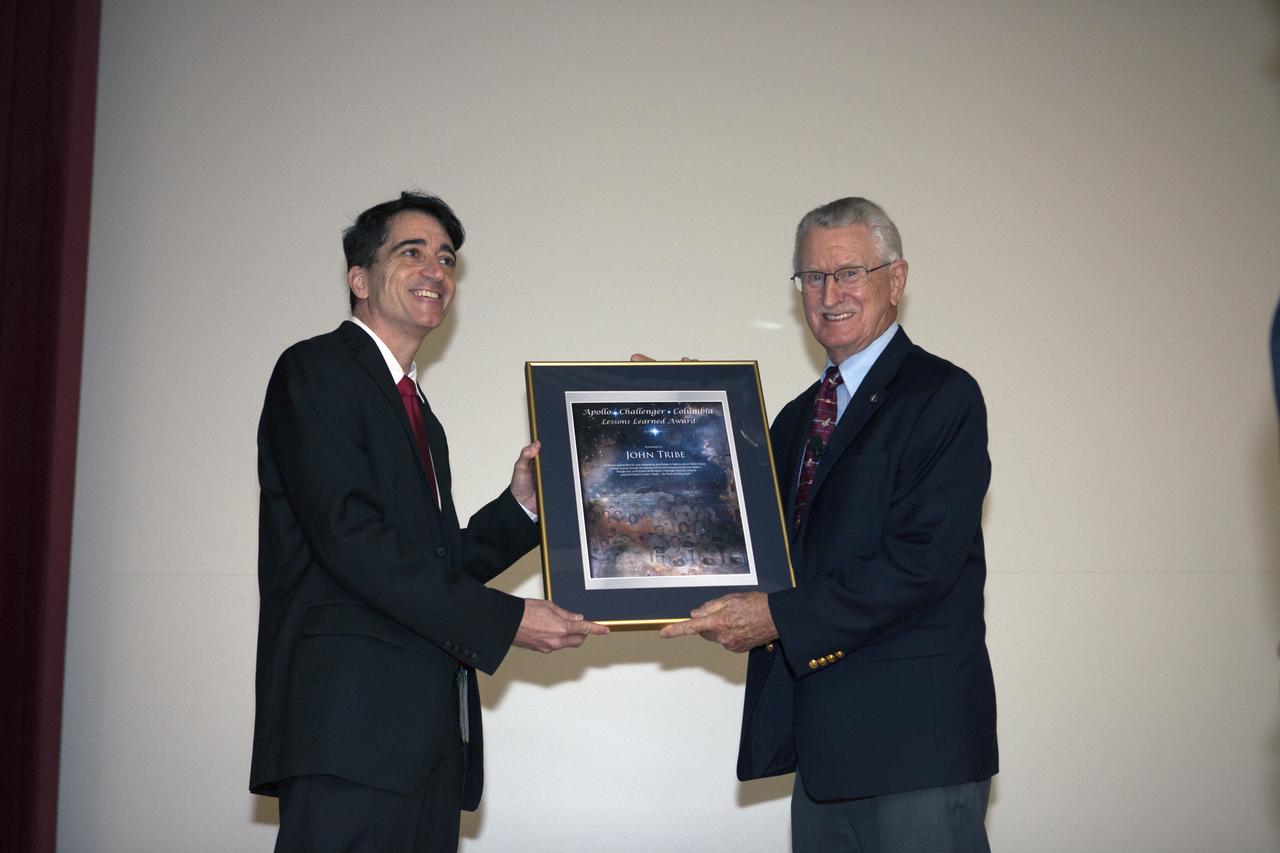 Mike Ciannilli, at left, the Apollo, Challenger, Columbia Lessons Learned Program manager, presents a certificate to John Tribe, retired, Apollo 1 Reaction and Control System lead engineer, during the Apollo 1 Lessons Learned presentation in the Training Auditorium at NASA's Kennedy Space Center in Florida. The theme of the program was "To there and Back Again." The event helped pay tribute to the Apollo 1 crew, Gus Grissom, Ed White II, and Roger Chaffee. 