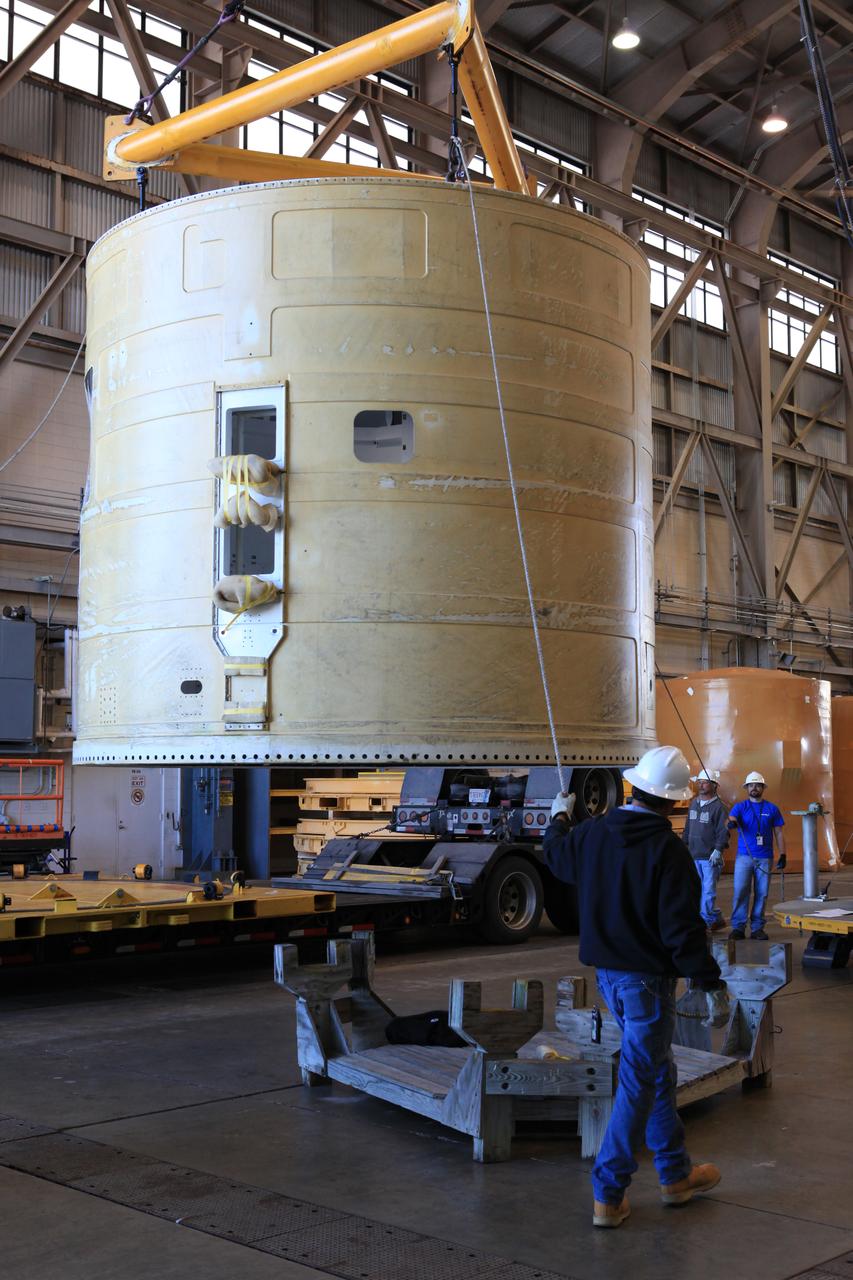 Technicians with Orbital ATK assist as a crane lifts the left-hand forward skirt for NASA's Space Launch System (SLS) solid rocket boosters away from a flatbed truck inside the Hangar AF facility at Cape Canaveral Air Force Station in Florida. The forward skirt was transported from booster prime contractor Orbital ATK in Promontory, Utah. The forward skirt will be staged in Hangar AF where refurbishment will continue. It will be inspected and prepared for use on the left-hand solid rocket booster for Exploration Mission 1. NASA's Orion spacecraft will fly atop the SLS rocket on its first uncrewed flight test. 