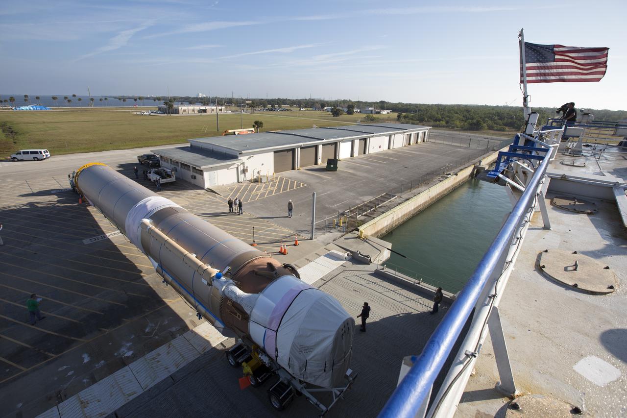 The United Launch Alliance (ULA) Atlas V booster arrives for the Orbital ATK CRS-7 commercial resupply mission to the International Space Station. A transport truck is taking the Atlas V from the Mariner cargo ship in the background, to the hangar at the Atlas Spaceflight Operations Center (ASOC), located south of Space Launch Complex 41 at Cape Canaveral Air Force Station. Scheduled to launch March 19, 2017, the Orbital ATK CRS-7 mission will lift off atop the ULA Atlas V rocket to deliver thousands of pounds of supplies, equipment and scientific research materials that improve life on Earth and drive progress toward future space exploration.