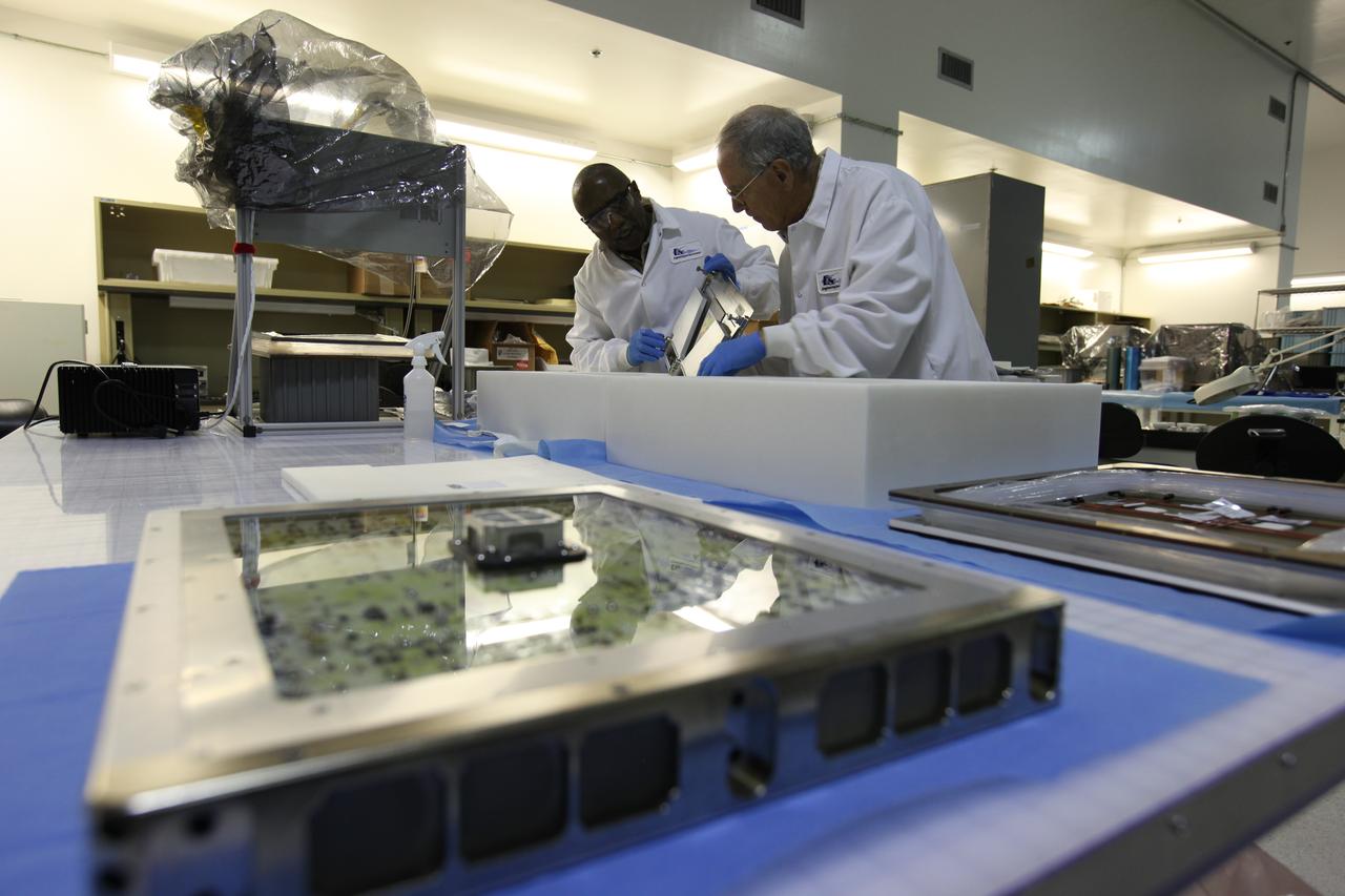 Charles Spern, at right, project manager on the Engineering Services Contract (ESC), and Glenn Washington, ESC quality assurance specialist, perform final inspections of the Veggie Series 1 plant experiment inside a laboratory in the Space Station Processing Facility at NASA's Kennedy Space Center in Florida. The Series 1 experiment is being readied for flight aboard Orbital ATK's Cygnus module on its seventh (OA-7) Commercial Resupply Services mission to the International Space Station. The Veggie system is on the space station.