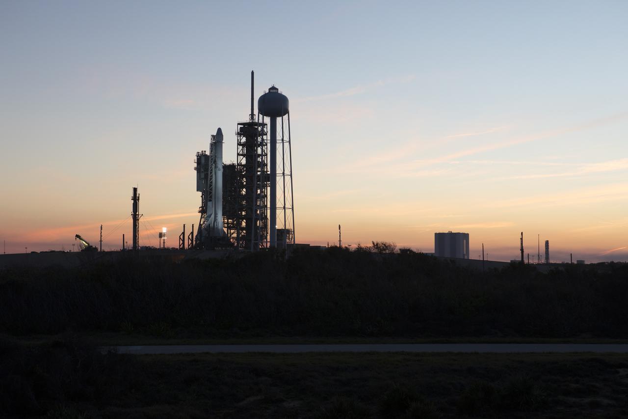 As sun sets, a Falcon 9 rocket stands ready for liftoff at the Kennedy Space Center's Launch Complex 39A. The historic launch site now is operated by SpaceX under a property agreement signed with NASA. In the background is the Vehicle Assembly Building. The rocket will boost a Dragon resupply spacecraft to the International Space Station. Liftoff is scheduled for 10:01 a.m. EST on Feb. 18. On its 10th commercial resupply services mission to the space station, Dragon will bring up 5,000 pounds of supplies, such as the Stratospheric Aerosol and Gas Experiment (SAGE) III instrument to further study ozone in the atmosphere. Once mounted on the space station, SAGE III will measure the Earth’s sunscreen, or ozone, along with other gases and aerosols, or tiny particles in the atmosphere.