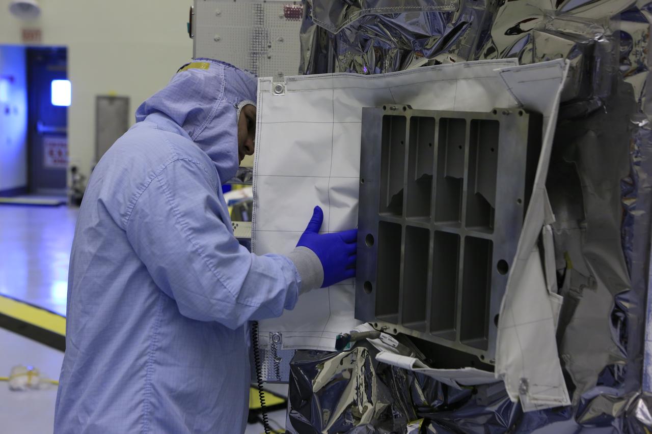 Inside the Payload Hazardous Servicing Facility at NASA's Kennedy Space Center in Florida, a technician adjusts the thermal blankets around the area where several Nanoracks will be installed on the exterior of the Orbital ATK Cygnus pressurized cargo module. The Orbital ATK CRS-7 commercial resupply services mission to the International Space Station is scheduled to launch atop a United Launch Alliance Atlas V rocket from Space Launch Complex 41 at Cape Canaveral Air Force Station no earlier than March 21, 2017. Cygnus will deliver 7,600 pounds of supplies, equipment and scientific research materials to the space station.