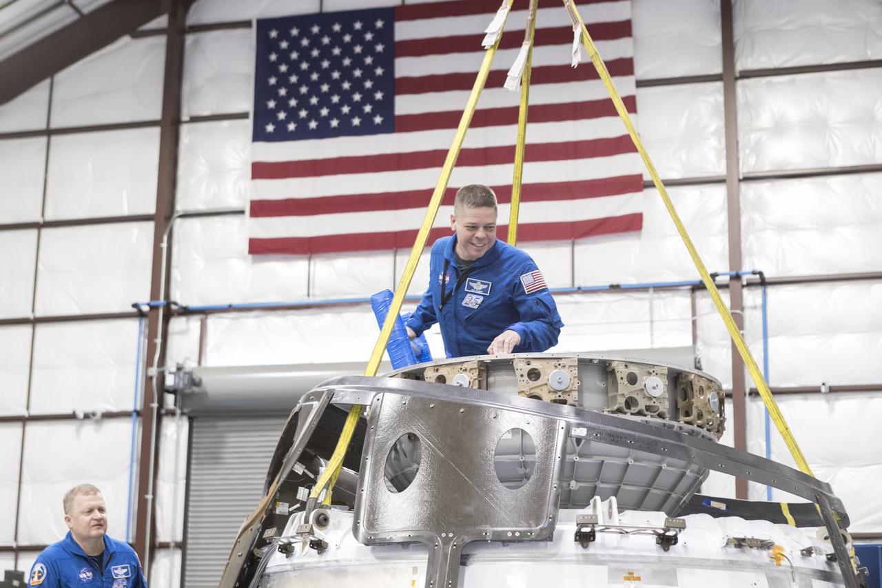 Astronaut Bob Behnken emerges from the top hatch of a SpaceX Crew Dragon spacecraft in manufacturing at SpaceX's headquarters and factory in Hawthorne, California, as astronaut Eri Boe looks on. Behnken and Boe are two of four NASA astronauts selected to train with Boeing and SpaceX ahead of flight tests for NASA's Commercial Crew Program. Along with Behnken and Boe, Doug Hurley and Suni Williams are working with the companies on their independent spacecraft and launch vehicles being developed to take astronauts to the International Space Station. Photo credit: SpaceX