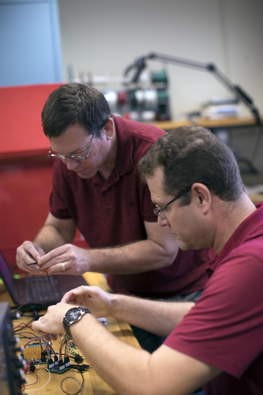 Curtis Ihlefeld, left, and Mark Lewis work with the prototype of the Flexible Damage Detection System in a laboratory with a prototype at NASA's Kennedy Space Center in Florida. The system uses circuits printed on thin thermal film and specialized software. The system is designed to show where damage to a surface occurs and how severe it may be. It could offer astronauts a real-time update on their spacecraft's condition during a mission without requiring a spacewalk. 