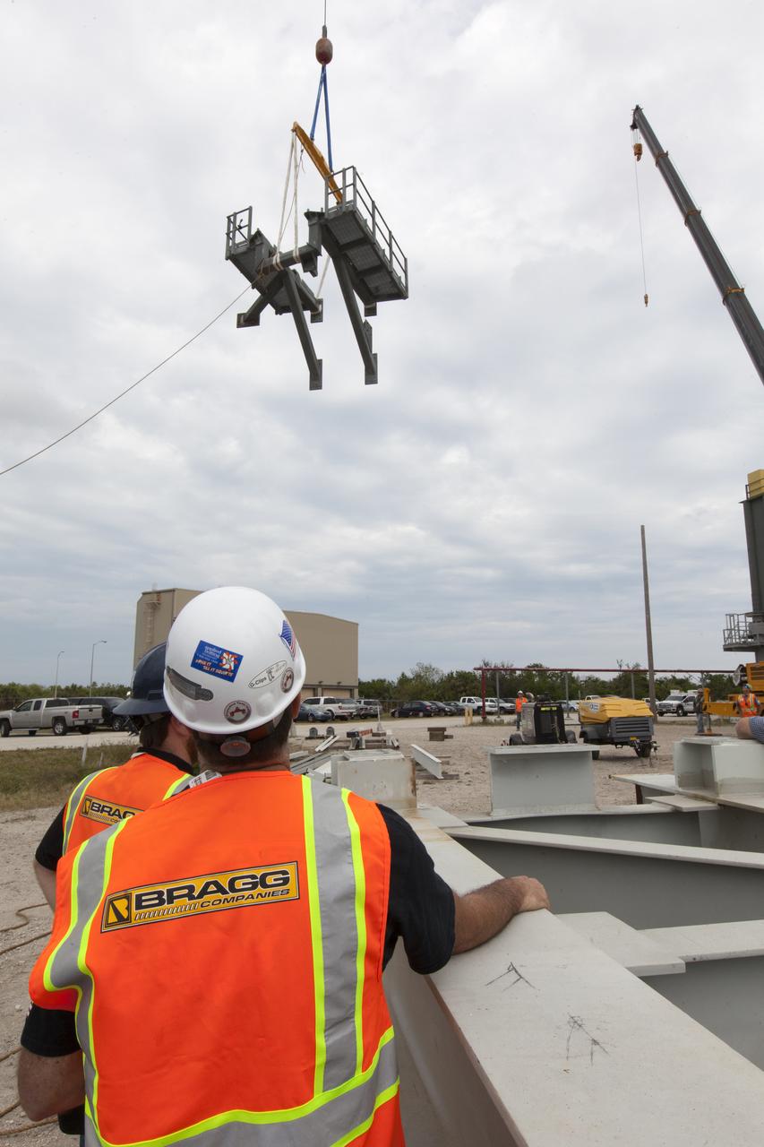 Crane specialists monitor the progress as the bracket for the Orion Service Module Umbilical (OSMU) is lifted up for installation on the mobile launcher tower at NASA's Kennedy Space Center in Florida. The mobile launcher tower will be equipped with a number of lines, called umbilicals, that will connect to the Space Launch System rocket and Orion spacecraft for Exploration Mission-1 (EM-1). The OSMU will be located high on the mobile launcher tower and, prior to launch, will transfer liquid coolant for the electronics and air for the Environmental Control System to the Orion service module that houses these critical systems to support the spacecraft. EM-1 is scheduled to launch in 2018. The Ground Systems Development and Operations Program is overseeing installation of the umbilicals.