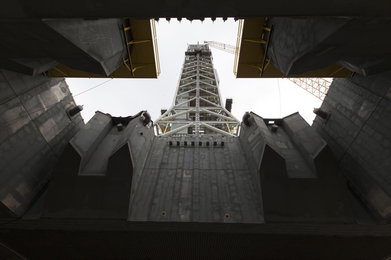 A view from below the mobile launcher shows a crane positioning the bracket for the Orion Service Module Umbilical (OSMU) high up for installation on the mobile launcher tower at NASA's Kennedy Space Center in Florida. The mobile launcher tower will be equipped with a number of lines, called umbilicals, that will connect to the Space Launch System rocket and Orion spacecraft for Exploration Mission-1 (EM-1). The OSMU will be located high on the mobile launcher tower and, prior to launch, will transfer liquid coolant for the electronics and air for the Environmental Control System to the Orion service module that houses these critical systems to support the spacecraft. EM-1 is scheduled to launch in 2018. The Ground Systems Development and Operations Program is overseeing installation of the umbilicals.