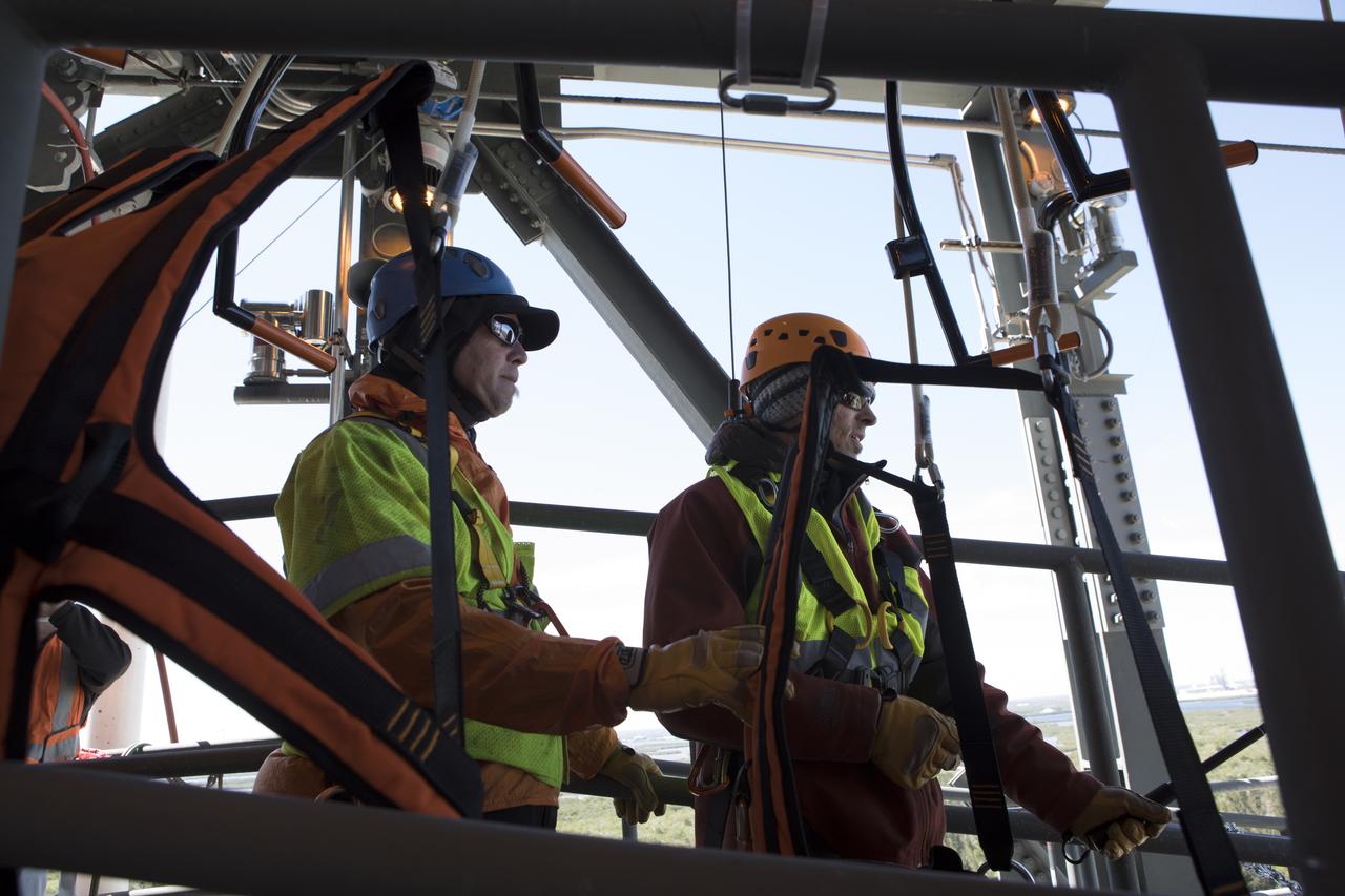 Two engineers prepare to evaluate the Emergency Egress System as they ride in folding seats attached to slide wires at Space Launch Complex 41. United Launch Alliance and Boeing continue modifications to the pad in order to host missions by the Boeing CST-100 Starliner carrying astronauts and crew. The system recently completed its final test. In the unlikely event of an emergency prior to liftoff, each person on the Crew Access Tower would get into their own seat attached to the wire and slide more than 1,340 feet to a safe area. The wires are situated 172 feet above the pad deck on level 12 of the tower. The Starliner will launch on a ULA Atlas V on mission to low-Earth orbit including those flying astronauts to the International Space Station during missions by NASA's Commercial Crew Program.