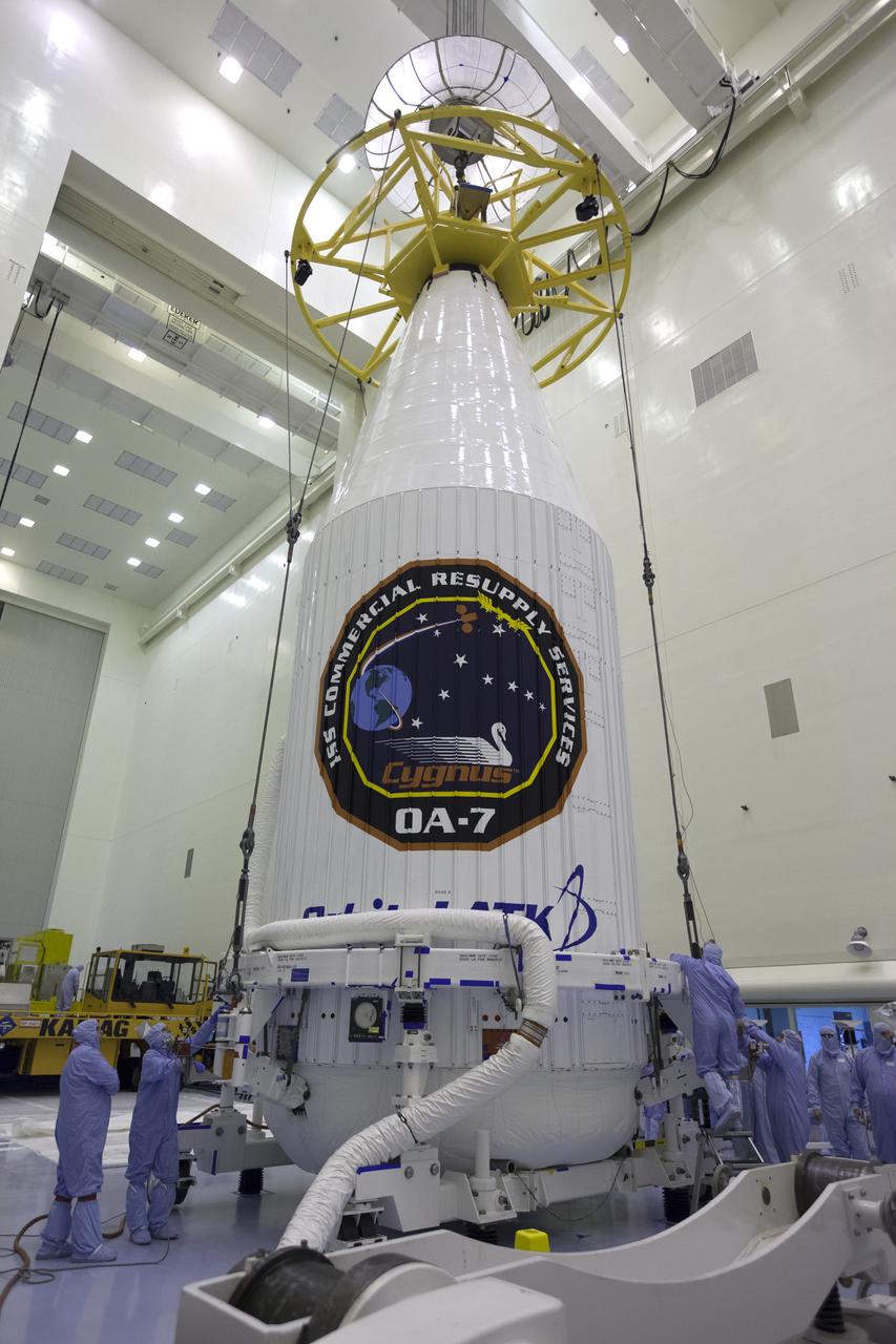 Inside the Payload Hazardous Servicing Facility at NASA's Kennedy Space Center in Florida, technicians assist as a crane is used to lift the Orbital ATK Cygnus pressurized cargo module, enclosed in its payload fairing, for transfer to a KAMAG transporter. The Orbital ATK CRS-7 commercial resupply services mission to the International Space Station is scheduled to launch atop a United Launch Alliance Atlas V rocket from Space Launch Complex 41 at Cape Canaveral Air Force Station. Cygnus will deliver 7,600 pounds of supplies, equipment and scientific research materials to the space station.