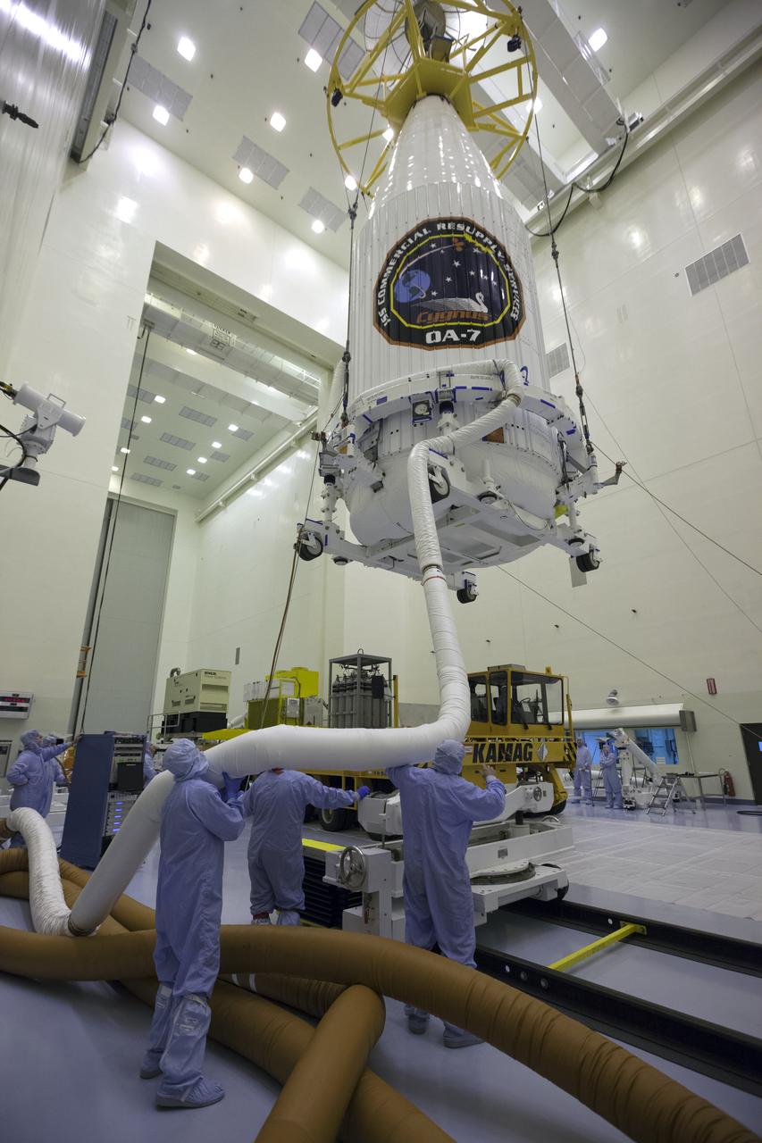Inside the Payload Hazardous Servicing Facility at NASA's Kennedy Space Center in Florida, technicians assist as a crane is used to lift the Orbital ATK Cygnus pressurized cargo module, enclosed in its payload fairing, for transfer to a KAMAG transporter. The Orbital ATK CRS-7 commercial resupply services mission to the International Space Station is scheduled to launch atop a United Launch Alliance Atlas V rocket from Space Launch Complex 41 at Cape Canaveral Air Force Station. Cygnus will deliver 7,600 pounds of supplies, equipment and scientific research materials to the space station.