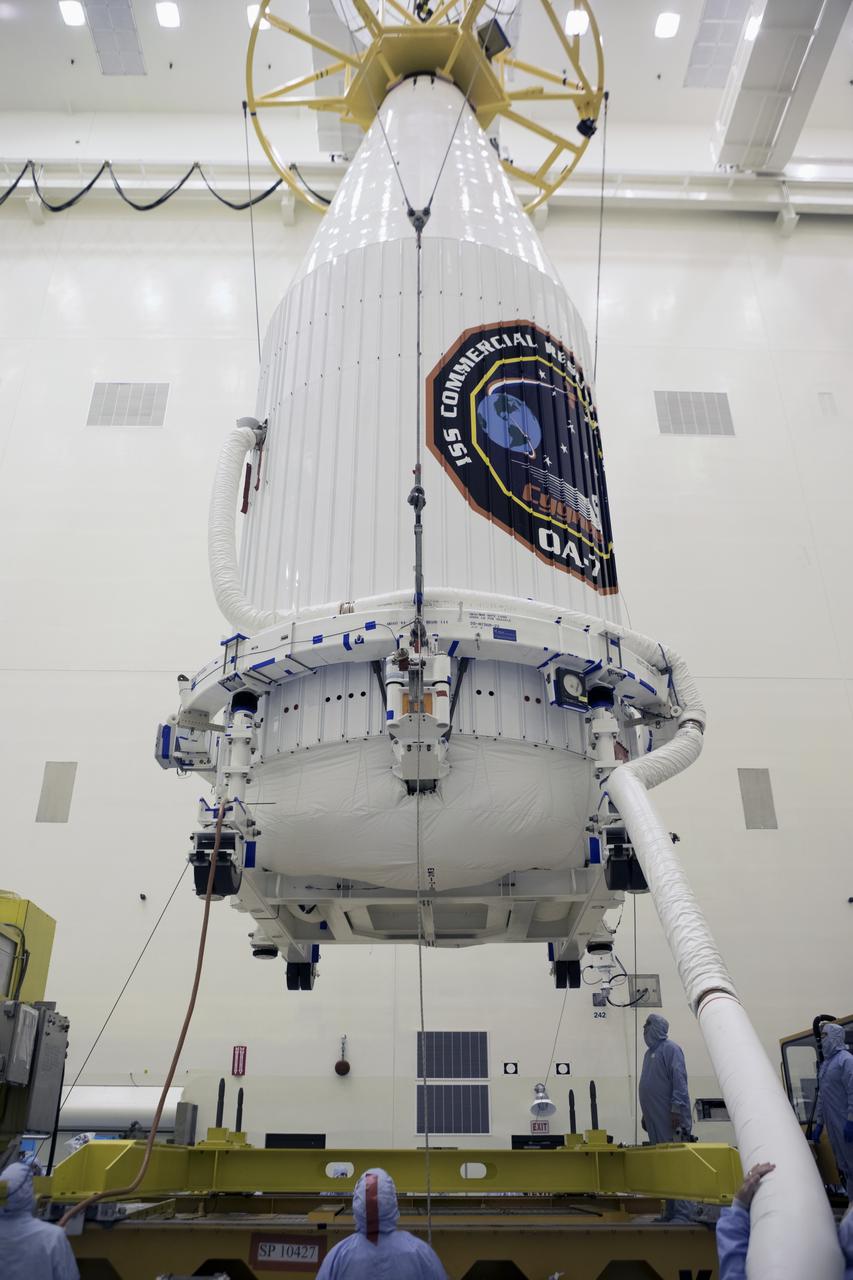 Inside the Payload Hazardous Servicing Facility at NASA's Kennedy Space Center in Florida, technicians monitor the progress as a crane lowers the Orbital ATK Cygnus pressurized cargo module, enclosed in its payload fairing, onto a KAMAG transporter. The Orbital ATK CRS-7 commercial resupply services mission to the International Space Station is scheduled to launch atop a United Launch Alliance Atlas V rocket from Space Launch Complex 41 at Cape Canaveral Air Force Station. Cygnus will deliver 7,600 pounds of supplies, equipment and scientific research materials to the space station.