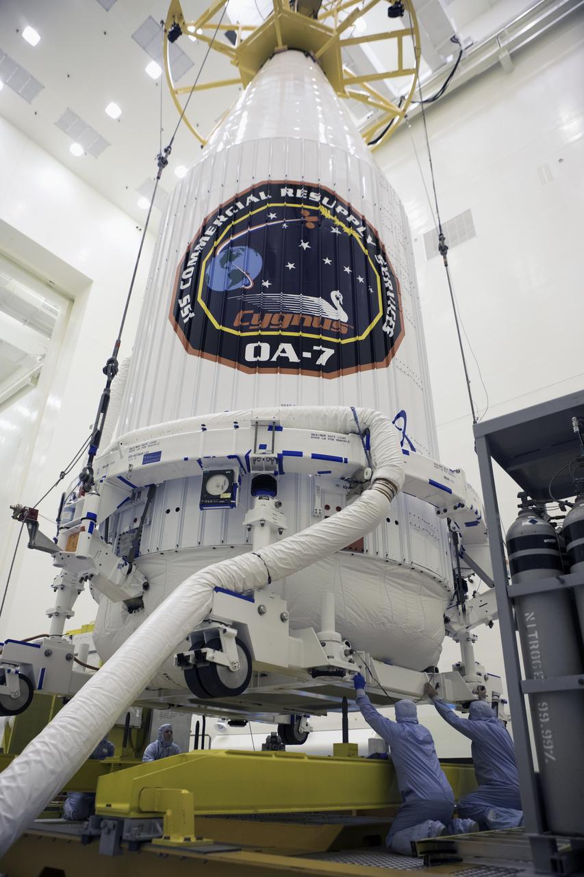 Inside the Payload Hazardous Servicing Facility at NASA's Kennedy Space Center in Florida, technicians assist as a crane lowers the Orbital ATK Cygnus pressurized cargo module, enclosed in its payload fairing, onto a KAMAG transporter. The Orbital ATK CRS-7 commercial resupply services mission to the International Space Station is scheduled to launch atop a United Launch Alliance Atlas V rocket from Space Launch Complex 41 at Cape Canaveral Air Force Station. Cygnus will deliver 7,600 pounds of supplies, equipment and scientific research materials to the space station.