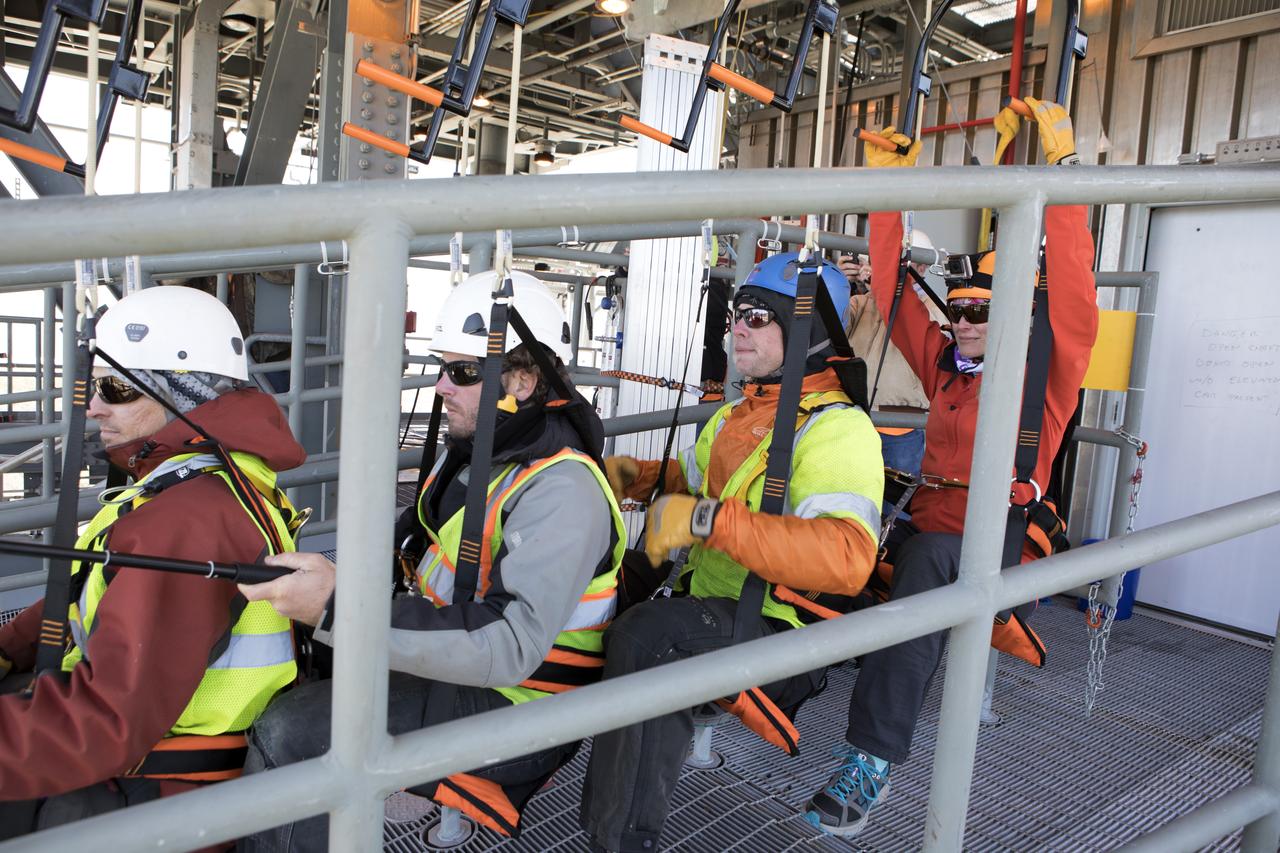 Engineers prepare to evaluate the Emergency Egress System as they ride in folding seats attached to slide wires at Space Launch Complex 41. United Launch Alliance and Boeing continue modifications to the pad in order to host missions by the Boeing CST-100 Starliner carrying astronauts and crew. The system recently completed its final test. In the unlikely event of an emergency prior to liftoff, each person on the Crew Access Tower would get into their own seat attached to the wire and slide more than 1,340 feet to a safe area. The wires are situated 172 feet above the pad deck on level 12 of the tower. The Starliner will launch on a ULA Atlas V on mission to low-Earth orbit including those flying astronauts to the International Space Station during missions by NASA's Commercial Crew Program.