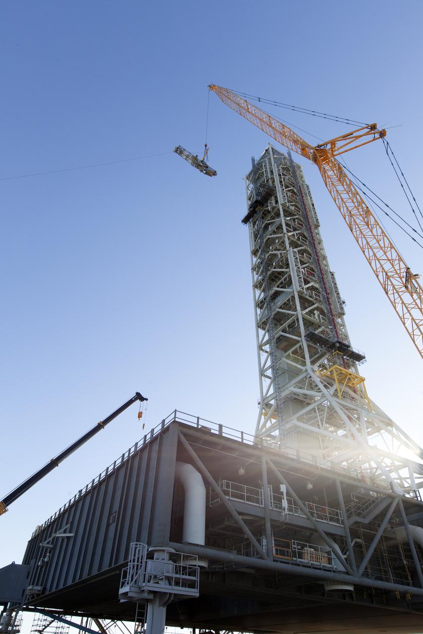 A crane lifts the Orion Service Module Umbilical (OSMU) high up for installation on the mobile launcher tower at NASA's Kennedy Space Center in Florida. The mobile launcher tower will be equipped with a number of lines, called umbilicals, that will connect to the Space Launch System rocket and Orion spacecraft for Exploration Mission-1 (EM-1). The OSMU will be located high on the mobile launcher tower and, prior to launch, will transfer liquid coolant for the electronics and air for the Environmental Control System to the Orion service module that houses these critical systems to support the spacecraft. EM-1 is scheduled to launch in 2018. The Ground Systems Development and Operations Program is overseeing installation of the umbilicals.