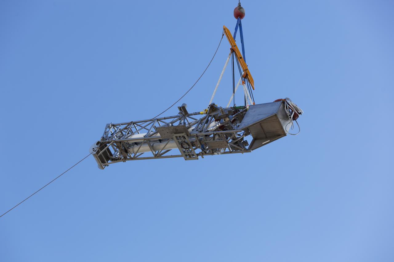Seeming to hang in midair, the Orion Service Module Umbilical (OSMU) is lifted high up by crane for installation on the mobile launcher tower at NASA's Kennedy Space Center in Florida. The mobile launcher tower will be equipped with a number of lines, called umbilicals, that will connect to the Space Launch System rocket and Orion spacecraft for Exploration Mission-1 (EM-1). The OSMU will be located high on the mobile launcher tower and, prior to launch, will transfer liquid coolant for the electronics and air for the Environmental Control System to the Orion service module that houses these critical systems to support the spacecraft. EM-1 is scheduled to launch in 2018. The Ground Systems Development and Operations Program is overseeing installation of the umbilicals. 