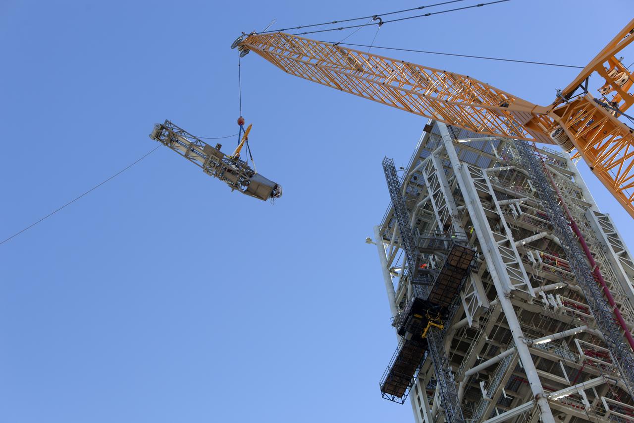 A crane and rigging are used to lift the Orion Service Module Umbilical (OSMU) high up for installation on the mobile launcher tower at NASA's Kennedy Space Center in Florida. The mobile launcher tower will be equipped with a number of lines, called umbilicals, that will connect to the Space Launch System rocket and Orion spacecraft for Exploration Mission-1 (EM-1). The OSMU will be located high on the mobile launcher tower and, prior to launch, will transfer liquid coolant for the electronics and air for the Environmental Control System to the Orion service module that houses these critical systems to support the spacecraft. EM-1 is scheduled to launch in 2018. The Ground Systems Development and Operations Program is overseeing installation of the umbilicals.