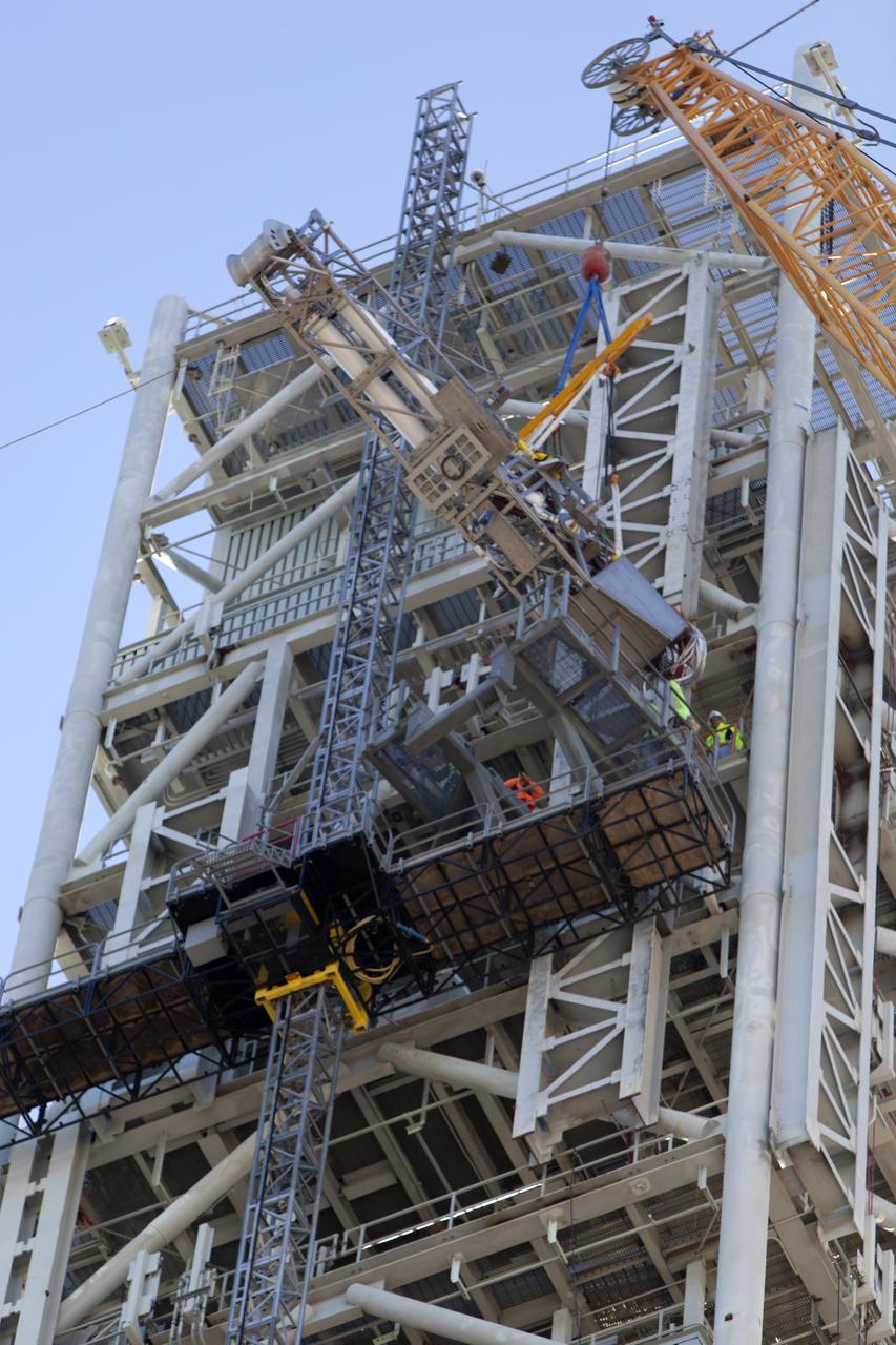 A crane and rigging are used to lift the Orion Service Module Umbilical (OSMU) high up for installation on the mobile launcher tower at NASA's Kennedy Space Center in Florida. The mobile launcher tower will be equipped with a number of lines, called umbilicals, that will connect to the Space Launch System rocket and Orion spacecraft for Exploration Mission-1 (EM-1). The OSMU will be located high on the mobile launcher tower and, prior to launch, will transfer liquid coolant for the electronics and air for the Environmental Control System to the Orion service module that houses these critical systems to support the spacecraft. EM-1 is scheduled to launch in 2018. The Ground Systems Development and Operations Program is overseeing installation of the umbilicals.